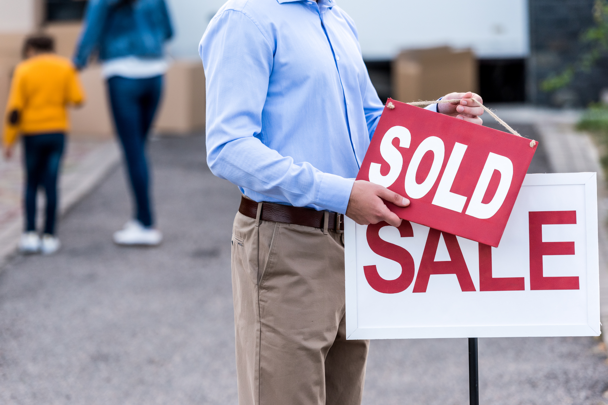 A realtor putting a sold sign in front of a house